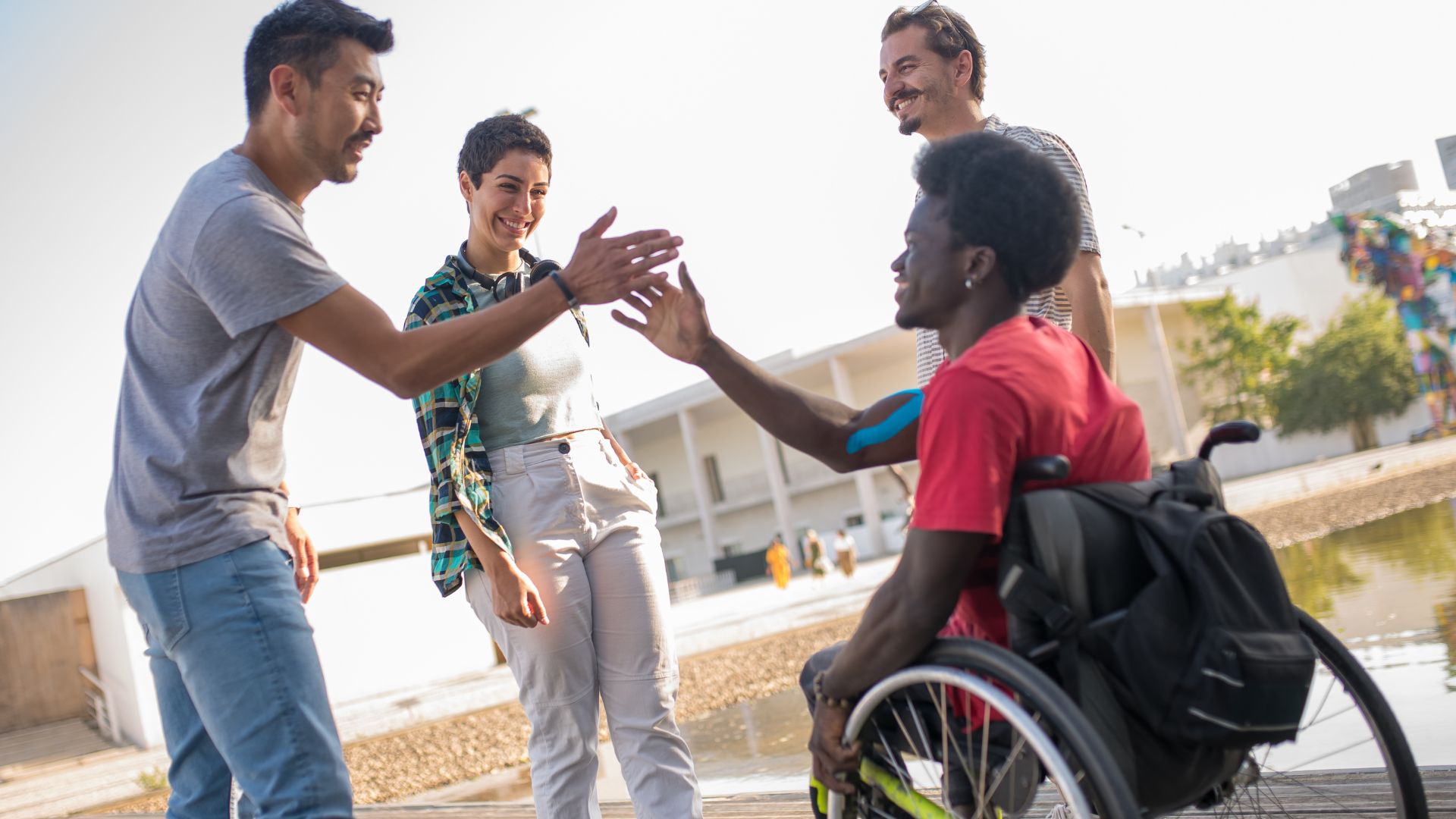 four happy people gathered, two of them slapping hands as a greeting